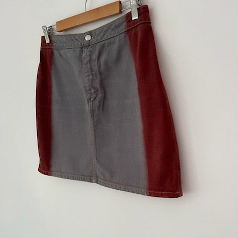 Two-tone skirt with red and gray sections on a hanger against a white background